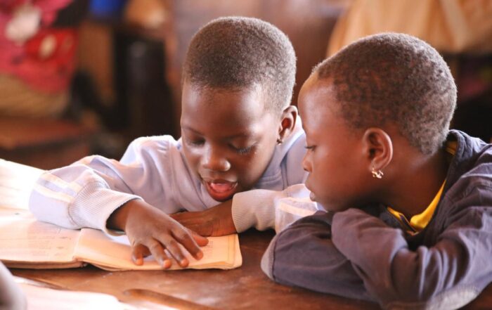 Young girls share a textbook in class Saka primary school.